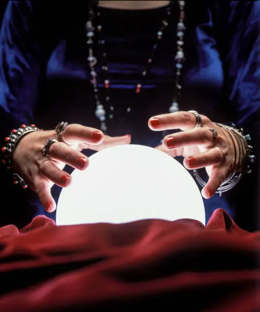 close up on female gypsy hands on a glowing crystal ball