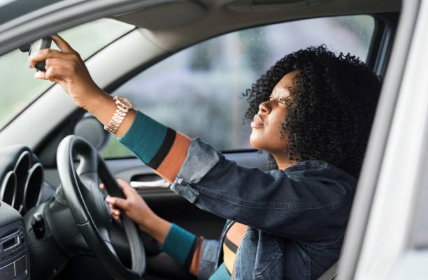Ensuring she has a clear view Shot of a mature african woman sitting in a car driving seat and adjusting rear view mirror rear view mirror stock pictures, royalty-free photos & images