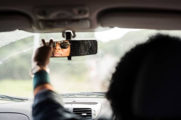 Making sure she has clear vision while driving Shot of a african woman adjusting rear view mirror while driving a car adjusting seat stock pictures, royalty-free photos & images