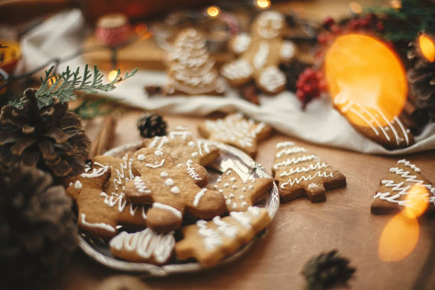 istock Merry Christmas. Festive gingerbread cookies with anise, cinnamon, pine cones, cedar branches and golden lights bokeh on rustic table. Atmospheric image. Seasons greetings 1184421802