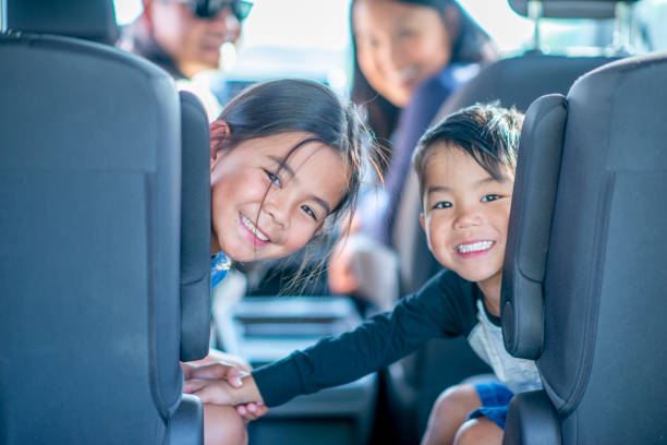 Mixed Race Family of Four Road Trip stock photo A mixed race family of four, consisting of a Mother, Father, son and daughter look out the back end of the vehicle. They are smiling and ready to start their road trip adventure. happy car asian stock pictures, royalty-free photos & images