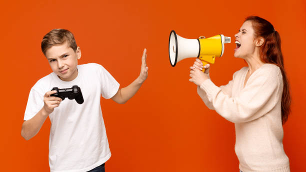 verärgerter teenager mit joystick ignoriert seine mutter mit lautsprecher - megaphone women at attention using voice stock-fotos und bilder