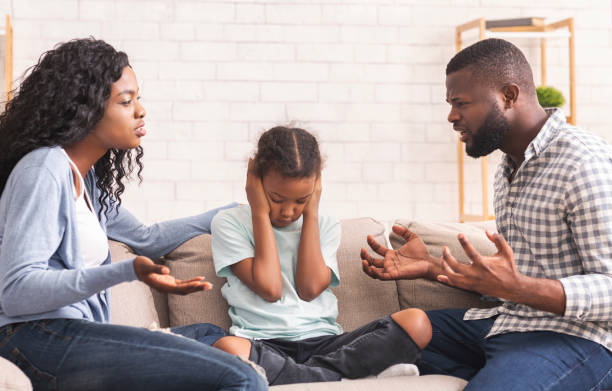 Depressed little black girl sitting between arguing parents, closing ears Depressed little black girl sitting between arguing parents, closing ears not to hear quarrels man closing ears photos stock pictures, royalty-free photos & images