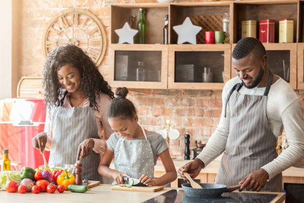 istock Cute afro girl helping parents at kitchen 1184423308