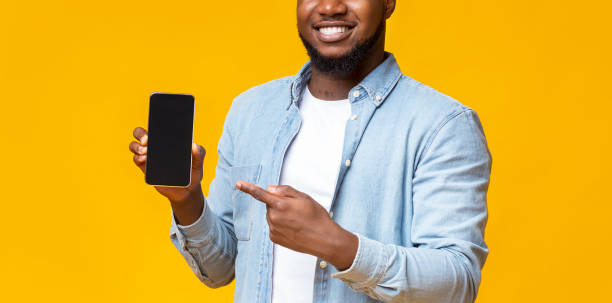 istock Guy holding cellphone with black screen and pointing on it 1184423410