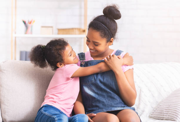 istock Cheerful african sisters embracing on couch at home 1184424615