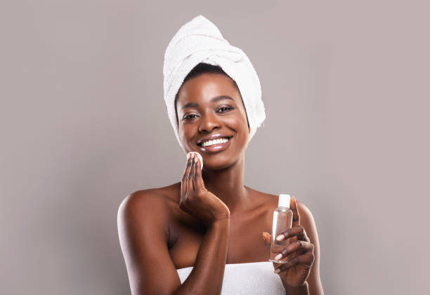 mujer negra limpiando la cara con almohadillas de algodón y agua micelar - human face water washing women fotografías e imágenes de stock