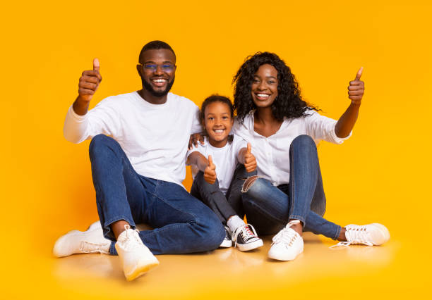 istock Happy Afro Family Gesturing Thumbs Up While Sitting On Floor 1184424888