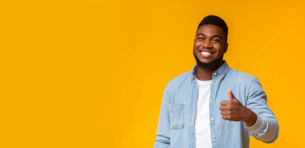 istock Happy african guy gesturing thumb up on yellow background 1184426133
