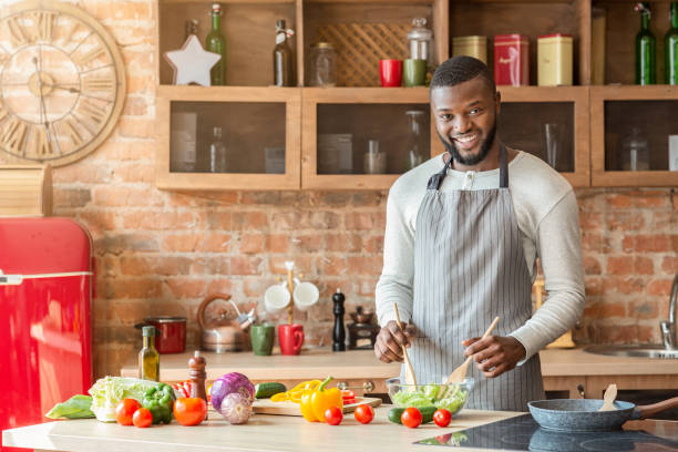 istock Smiling black man preparing fresh healthy salad at kitchen 1184426347