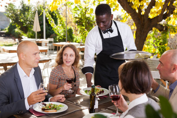 istock Waiter and four guests at open-air restaurant summer 1184431873