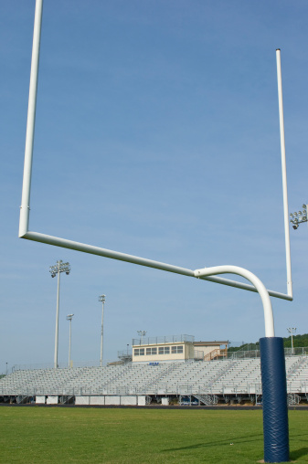 this photo is of a field goal and stadium on a American Football Field at Football Game. there is also the forty yard-line, thirty yard-line, twenty yard-line, ten yard-line and endzone in this picture. the football field is made of lush green grass or artificial turf. the photo is a professional football field. this photo was taken at a live sporting event. 