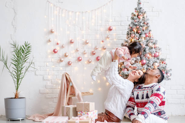 famille interraciale heureuse près de l'arbre de noel avec des cadeaux. - couple black american culture kissing photos et images de collection