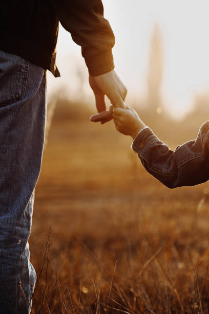 Colse up view of father and son hands Colse up view of father and son holding hands in backlight family holding hands stock pictures, royalty-free photos & images