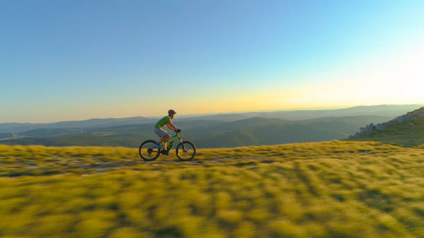 istock AERIAL: Flying along mountain biker pedalling his bicycle along the grassy trail 1184437962