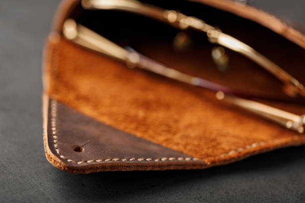 istock Genuine brown leather glasses case, handmade on a dark background. Glasses inside the case 1184437964