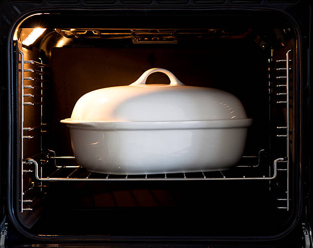 White porcelain baking dish with lid in open oven with light  switch on