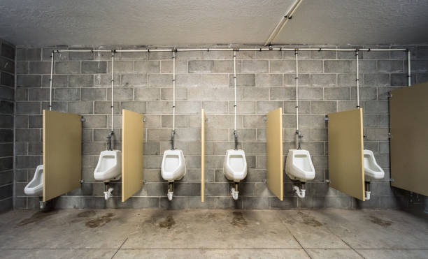 A series of urinals and privacy screens in a simple men's restroom