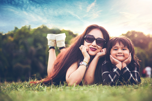 Mother and daughter lying on grass in park, 2 people selective focus and horizontal composition with copy space