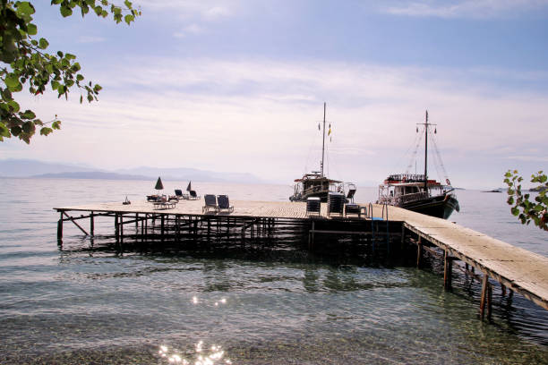 istock Tourist boat cruiser in small marina on sea and beautiful beach, waiting tourists for ship is sailing out of port for next tourist tour. Anchored cruise ship in harbor. Summer season, travel, holiday. 1184443473