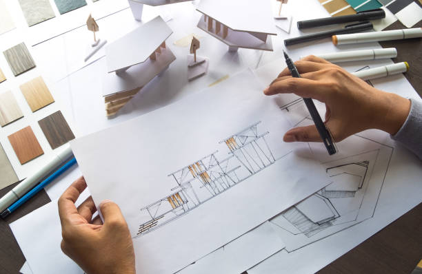 istock architect design working drawing sketch plans blueprints and making architectural construction model in architect studio 1184444502