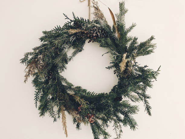 istock Stylish rustic wreath on white wall. Rural modern wreath hanging white wall background in room. Happy Holidays. Festive decoration. Phone photo 1184447292