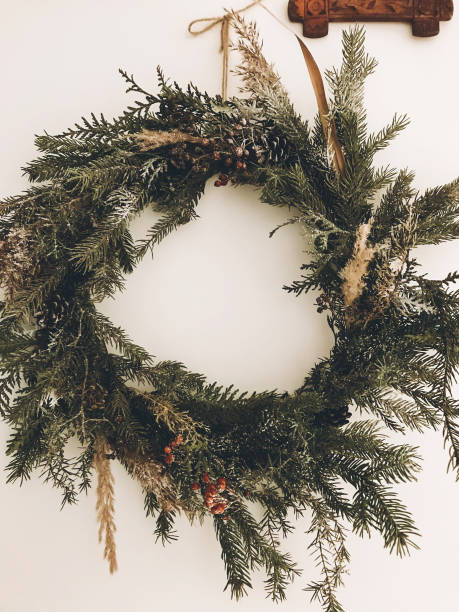 istock Stylish rustic wreath on white wall. Rural modern wreath hanging white wall background in room. Happy Holidays. Festive decoration. Phone photo 1184447670