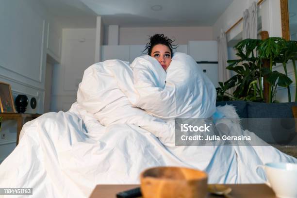 Young Attractive Anxious Woman Watching Tv Series And Wrapping In Big White Blanket Cold Autumn Or Winter Time Spending Stock Photo - Download Image Now