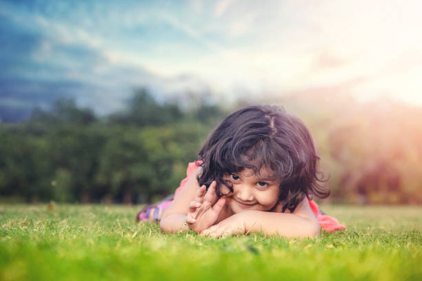 公園の草の上に横たわっている小さなかわいい女の子の笑顔 - baby child babies only baby girls ストックフォトと画像