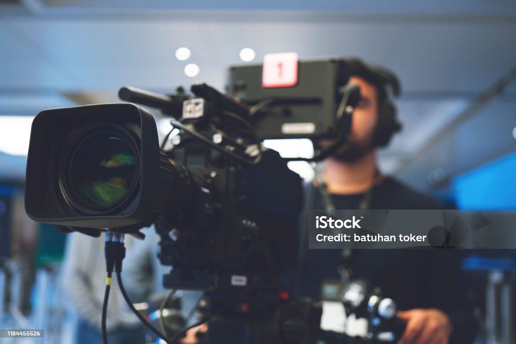 Professional cameraman with headphones with HD camcorder in live television Home Video Camera, Studio - Workplace, Filming, Television Set, Camera Operator Home Video Camera Stock Photo