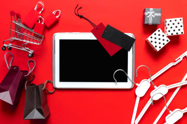 istock Creative top view  flat lay online shopping tablet, trolley with packages, gift boxes. Ecommerce concept, christmas shopping on red background 1184455747