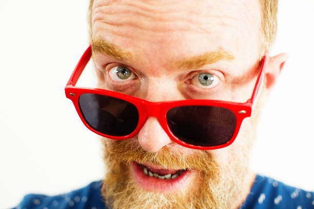 istock Bearded man looking quizzically over his red sunglasses 1184457391