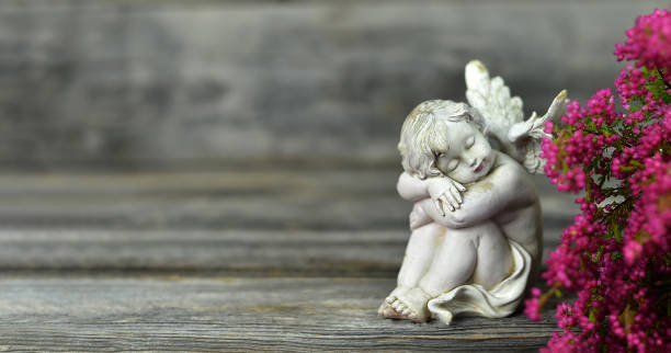 istock Angel and flowers on wood background 1184458623