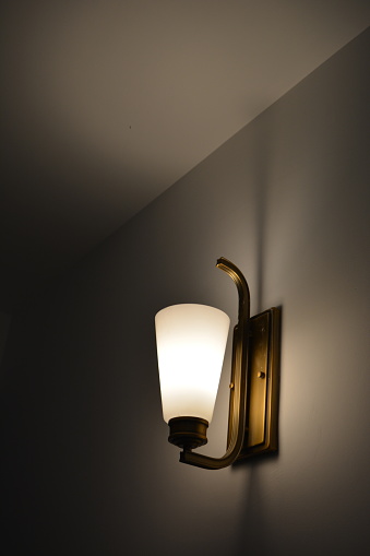 Yellow light of night wall lamp falling on room wall creating shadows