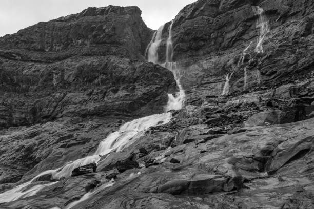 istock Black and white image of a waterfall shot with long exposure cascading down rugged rock face in Canada. 1184463794