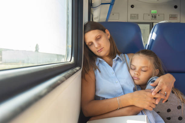 istock Mom and daughter hugging sleeping in a train car 1184466744