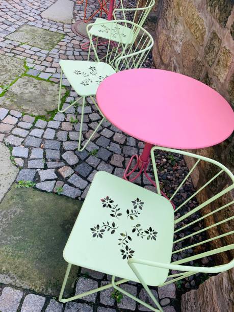istock Green chairs and pink tound table on cobblestone ground 1184467261