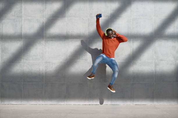uomo africano che salta per la gioia ascoltando musica - dancing dancer hip hop jumping foto e immagini stock