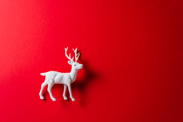 istock White reindeer toy on red background. 1184477486