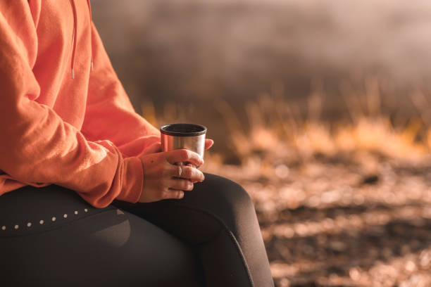 istock Woman drinking coffee outdoors by the lake 1184477644
