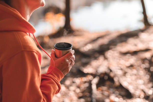 istock Woman drinking coffee outdoors by the lake 1184477655