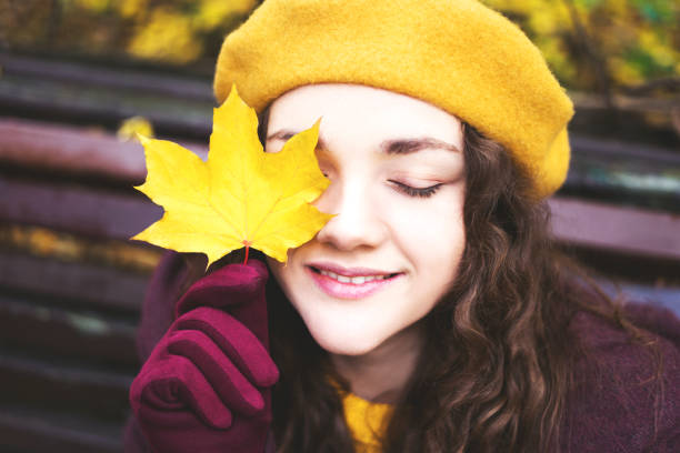 istock Girl in a yellow beret with maple leaf in her face. 1184477891