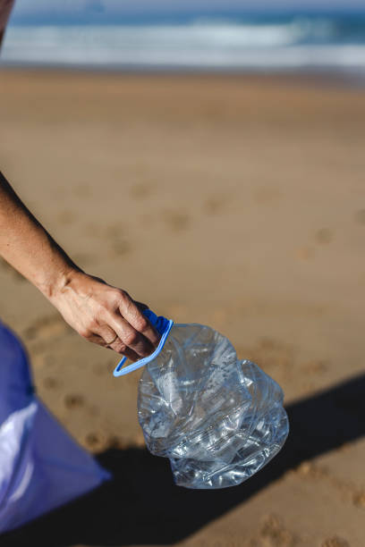 istock Woman picking up trash and plastics cleaning the beach 1184481665
