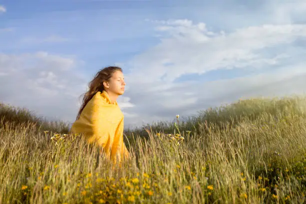 Adolescent mindfulness in a flower field, getting sunlight on her face.