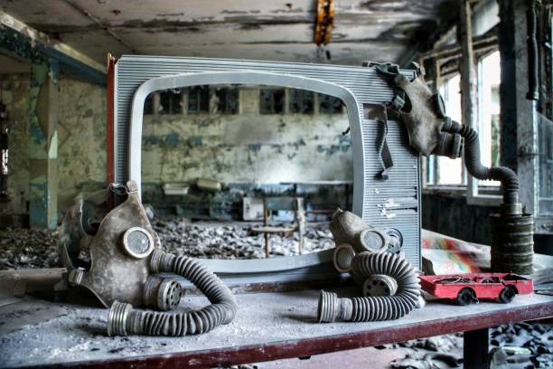 Gas masks arranged around a TV: Bizarre findings of the abandoned buildings of Pripyat, Chernobyl exclusion zone. Soviet-era gas masks are hung up on a weathered TV screen in an abandoned building in Pripyat, Ukraine, site of the 1986 Chernobyl nuclear desaster and center the Chernobyl exclusion zone. cold war photos stock pictures, royalty-free photos & images