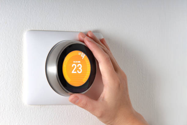 istock Smart Thermostat with a hand setting up the temperature 1184491046