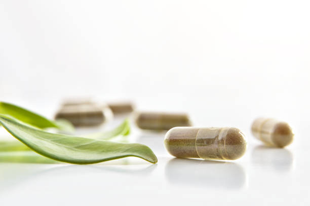 Natural medicine capsules and plant leaf on white table isolated white. Natural medicine concept. Front view. Horizontal composition.