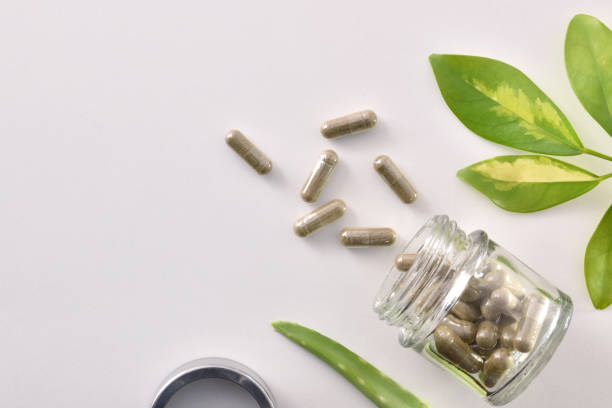 istock Natural medicine capsules in open glass jar lying on table 1184495056