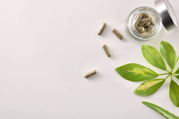 istock Natural medicine capsules in open glass jar on table top 1184495057
