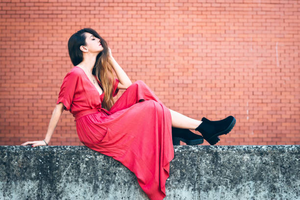 istock Beautiful young woman posing on front of brick wall 1184496608